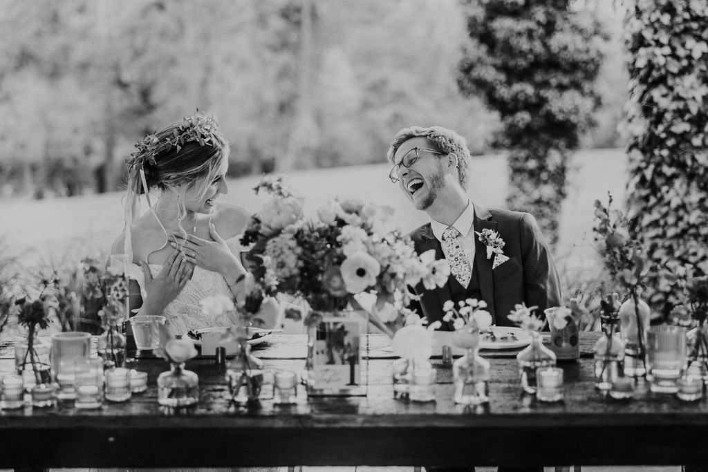 bride and groom laughing during speeches at their tented wedding reception